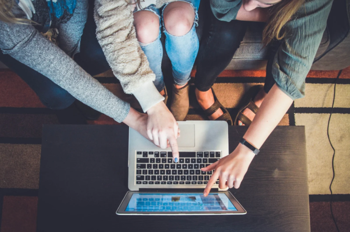 a teen and adults pointing to a laptop